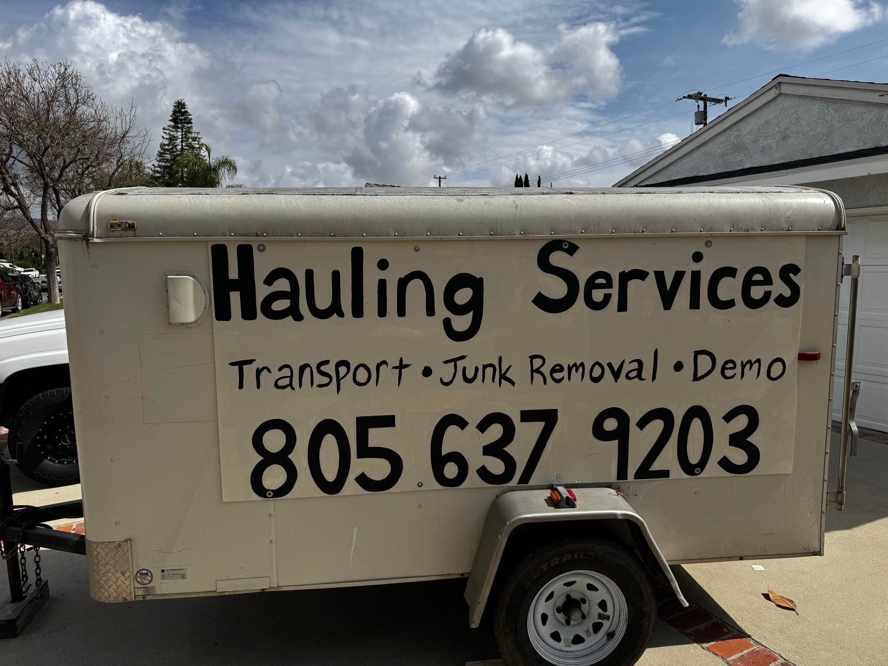 Branded enclosed trailer labeled for hauling services, junk removal, and demo work