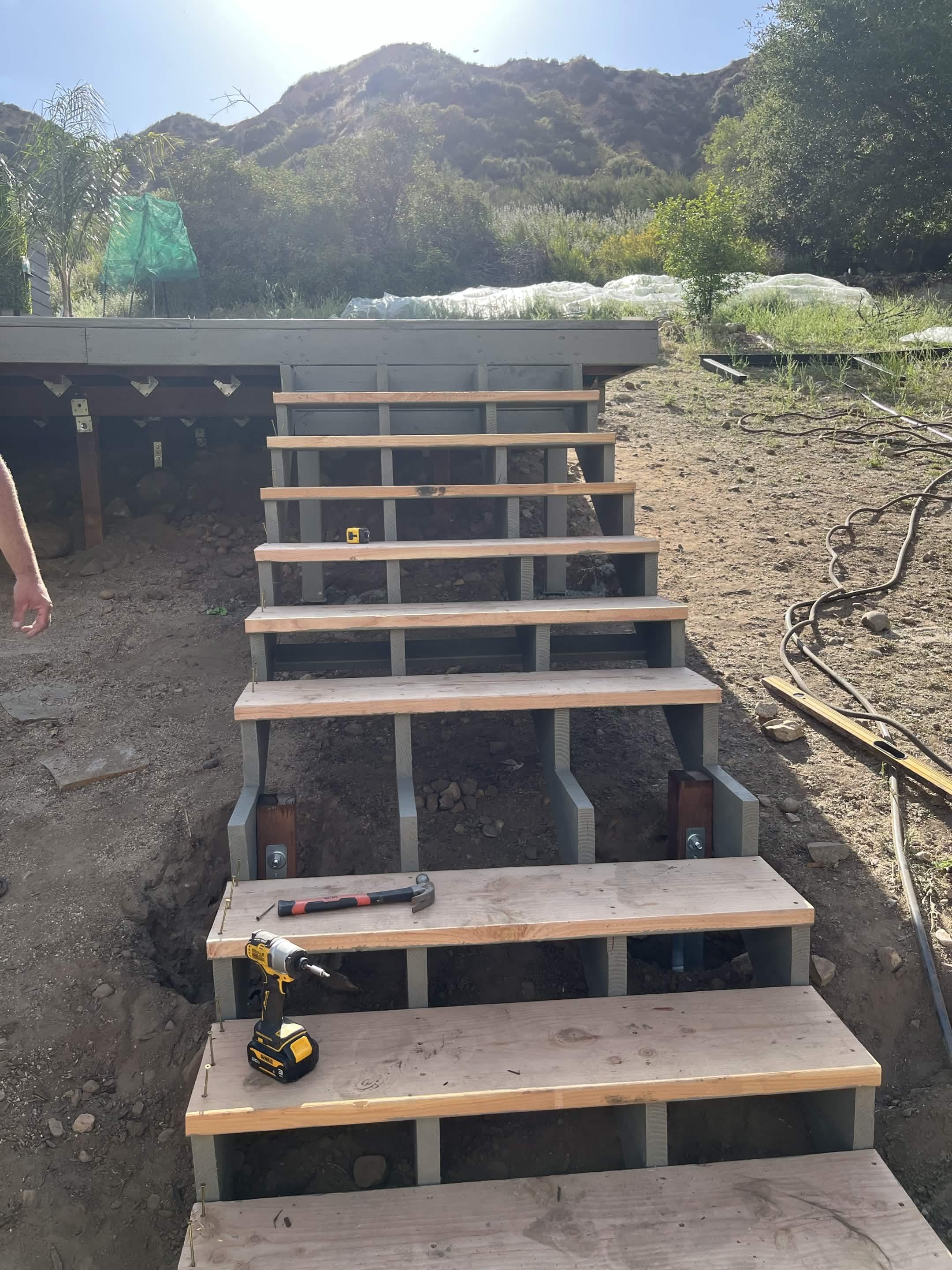 Outdoor hillside steps under construction leading up to a raised deck