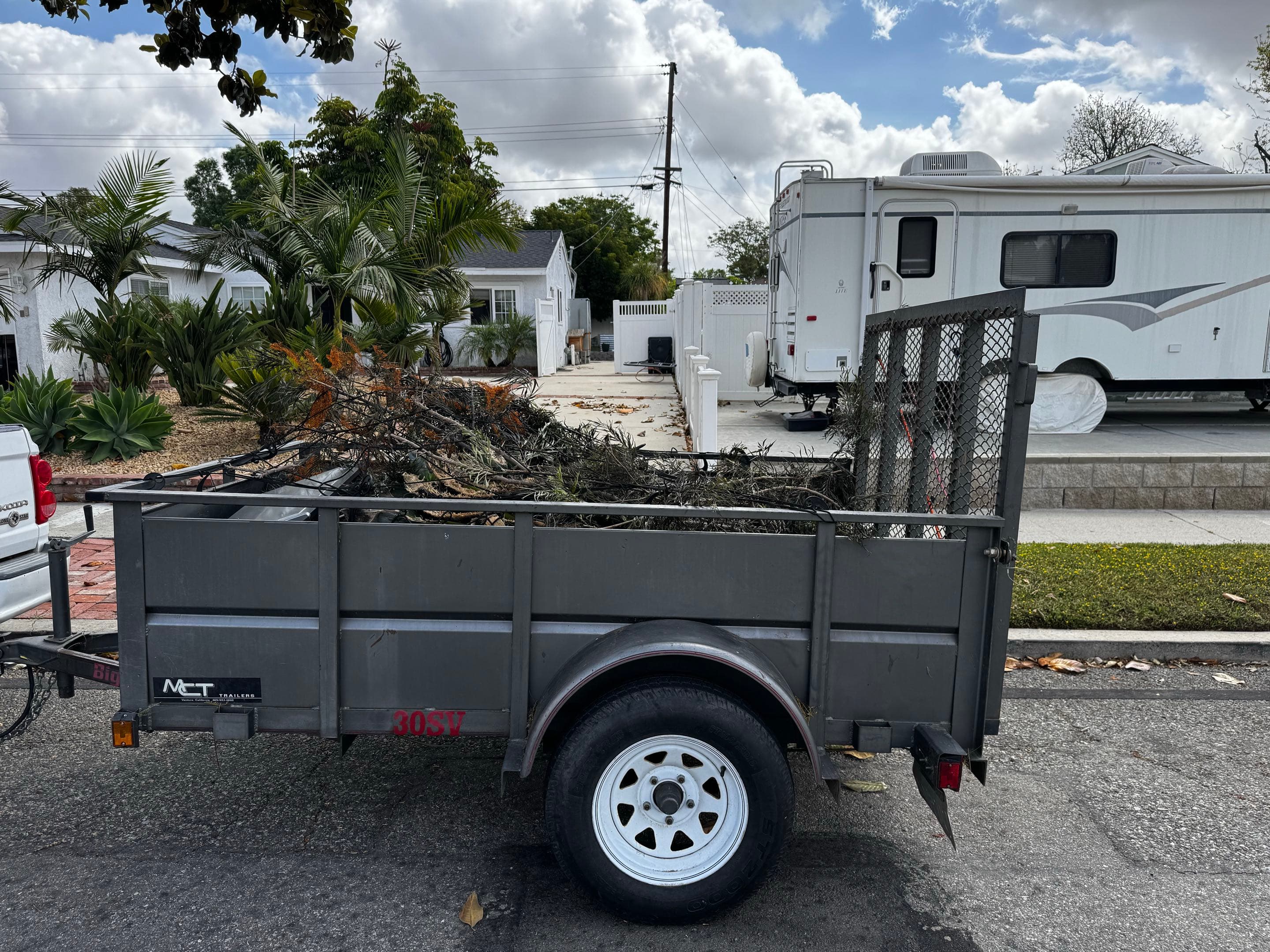Utility trailer loaded with cut branches and yard debris